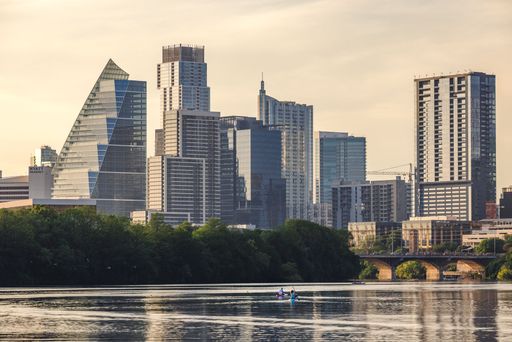 Skyline of Austin, Texas with modern skyscrapers and a serene river view during sunset.