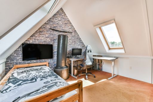 An interior shot of a bedroom with a TV on the wall under a roof