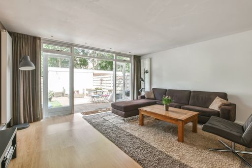 An interior shot of a living room with some furniture with white walls and wooded floor