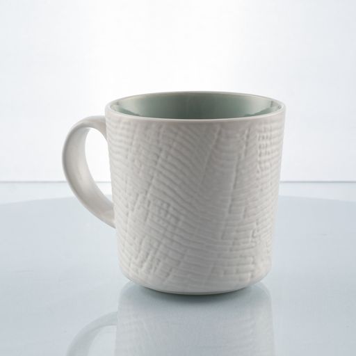 A white textured mug on a white background and glass table