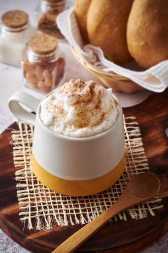 Mochaccino with extra cream and chocolate powder, with homemade bread on rustic wooden board