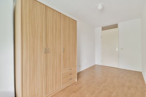 An interior shot of an empty room with a wardrobe in white walls and a wooden floor