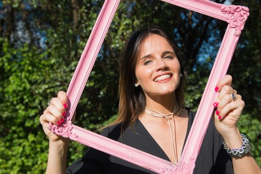 A young beautiful attractive sexy happy smiling Caucasian woman in a black dress holding a pink frame