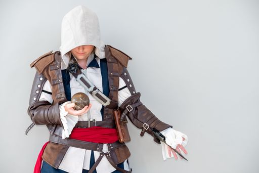A person in detailed medieval-style leather armor holding a spherical object, against a plain background.