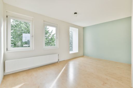 A beautiful renovated empty room interior with white walls and wooden floors