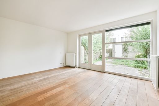 A beautiful renovated empty room interior with white walls and wooden floors
