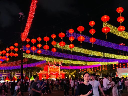 A vibrant night festival scene with colorful lanterns and lights, featuring a diverse crowd enjoying the lively atmosphere.