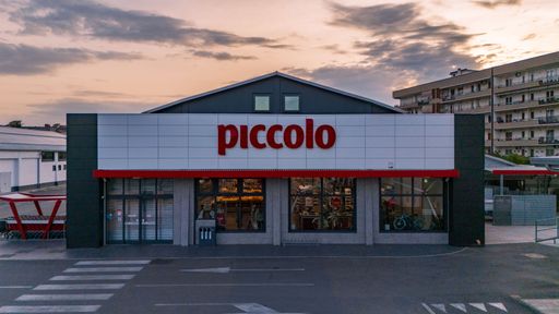 A morning view of Supermercati Piccolo in Santa Maria Capua Vetere, capturing the empty parking lot and soft dawn light from a slightly elevated persp