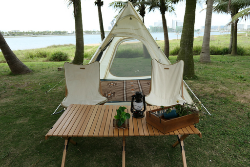 Beige camping setup with lounge chairs by the water, palm trees framing distant city skyline.