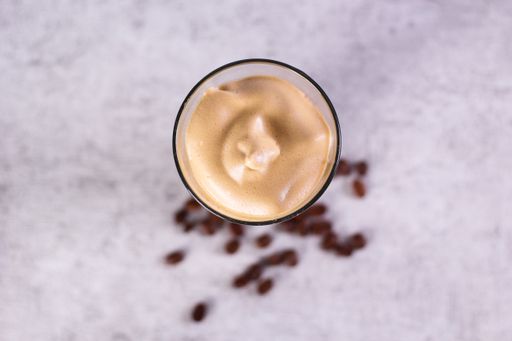 An overhead shot of a caramel smoothie surrounded by coffee beans