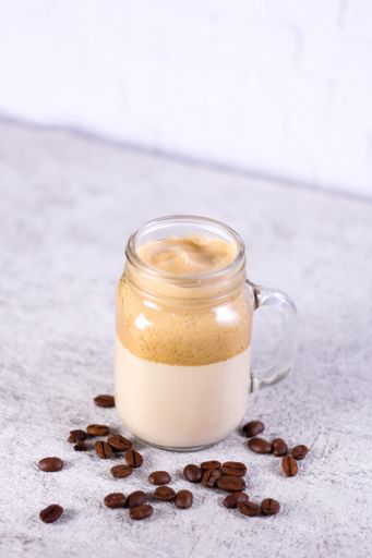 A vertical shot of a caramel smoothie surrounded by coffee beans on the table