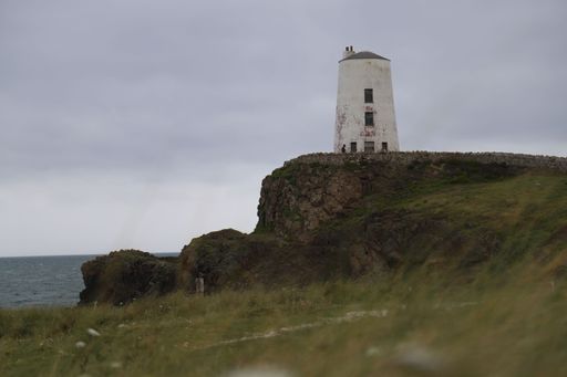 The Twr Mawr Lighthouse stands on a rocky cliff in Anglesey, Wales.