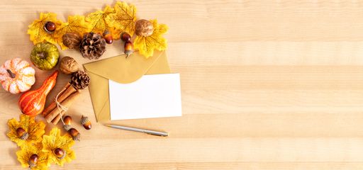 A top view shot of a wooden table with thanksgiving decors, envelopes with copy space, and a pen