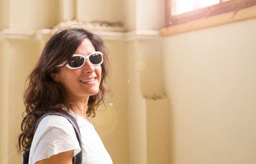 A portrait of a middle-aged smiling woman wearing sunglasses and looking at the camera