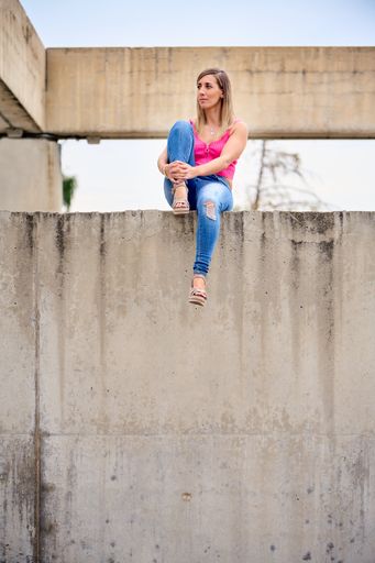 A vertical shot of a Spanish female sitting in a high place