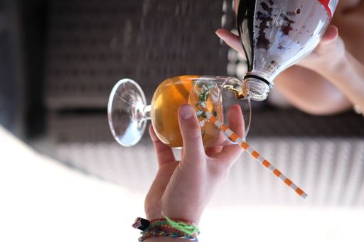 A vertical shot of a hand adding soda to the glass with another drink