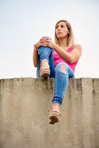 A vertical shot of a Spanish female sitting in a high place