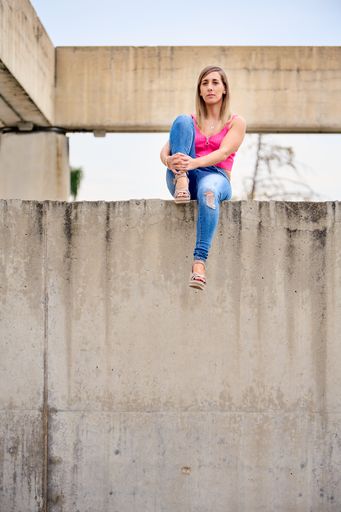 A vertical shot of a Spanish female sitting in a high place