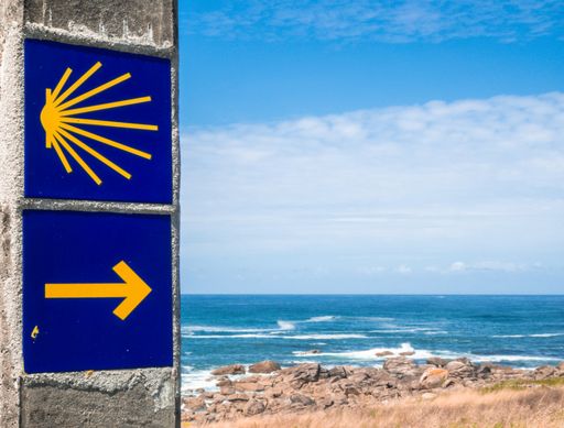 The picture shows a signpost with symbols of the Way of St James with the sea and blue skies in the background