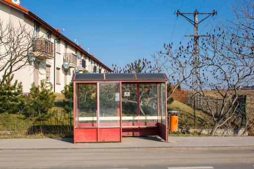 A red bus stop with no people on the street, Komorniki, Poland