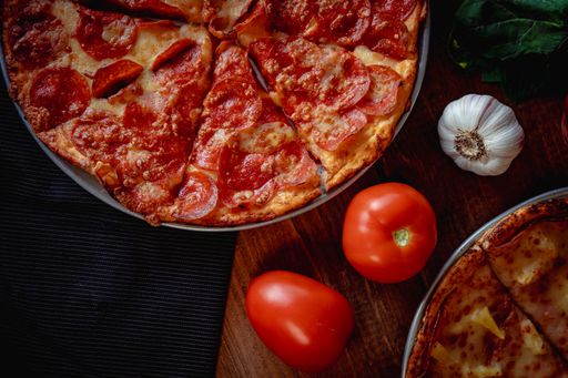 A closeup top view of a delicious pizza pepperoni and a salad  on a table with other ingredients