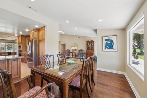 Spacious modern dining room with wooden furniture, large windows, and a view of the kitchen area in a cozy home interior.