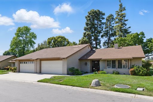 Suburban house with a spacious driveway and green lawn under a clear blue sky.