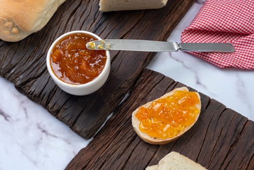 A top view of a breakfast board with sliced bread and a bowl of jam