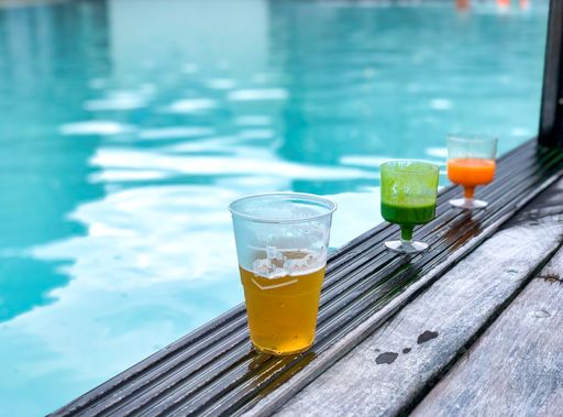 A closeup shot of different drinks near a pool of a hotel