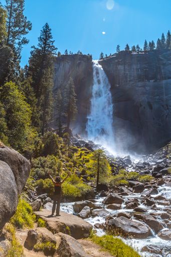 A vertical shot of a woman hiking in the Vernal Falls waterfall of Yosemite National Park in the USA