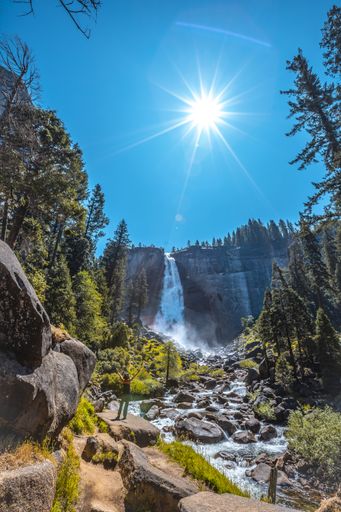A vertical shot of a woman hiking in the Vernal Falls waterfall of Yosemite National Park in the USA