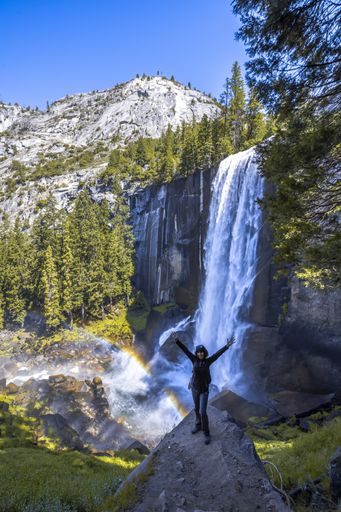 A vertical shot of a woman hiking in the Vernal Falls waterfall of Yosemite National Park in the USA