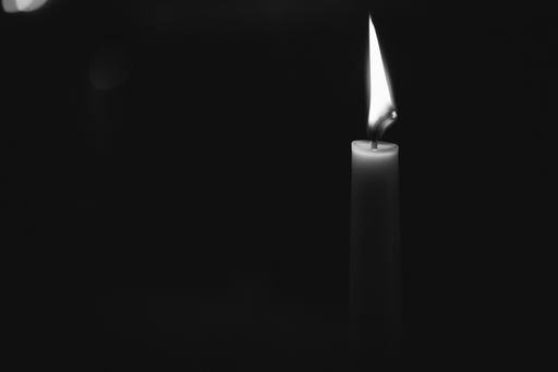 A grayscale of a burning candle isolated on a dark background
