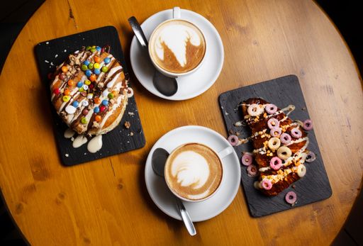 A top view of two cups of cappuccino with delicious croissant and donut