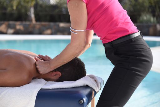 A young man enjoying massage near the swimming pool