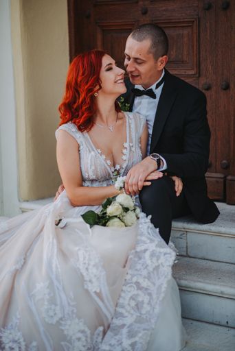 A vertical closeup of the bride and groom sitting on the stairs.