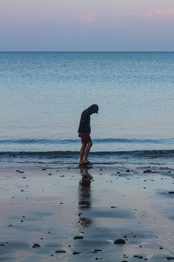 A vertical shot of a male at a beach during the rainy weather