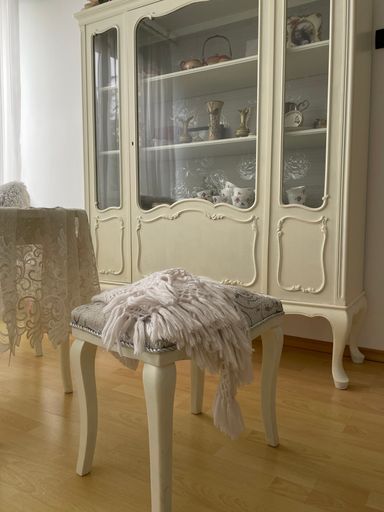 A vertical shot of a white luxurious cupboard and a chair in the room