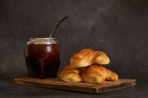 A beautiful shot of medialunas croissants and yerba mate infusion placed on a wooden cutting board
