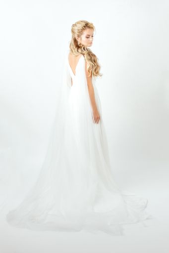 A vertical shot of a beautiful Caucasian bride in an elegant wedding dress posing on white background