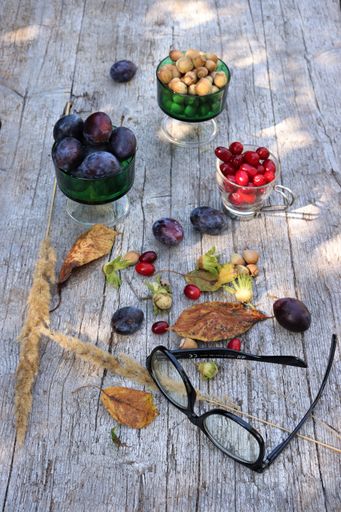 A vertical shot of autumn leaves, fruits and nuts on wooden surface as a beautiful fall background