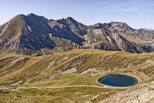 A beautiful view of the rocky green alps gleaming under the cloudy blue sky in Italy