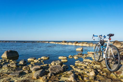 A view of a Bicycle at the front of rocky seaside with a blue sunny horizon sky in Mersrags, Latvia
