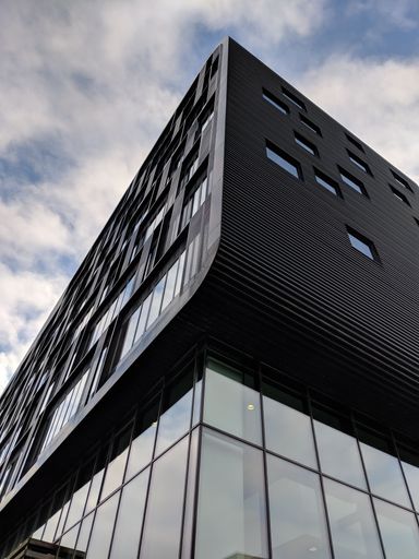 A vertical low angle shot of a high rise black building with glass windows