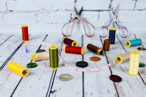 A closeup shot of accessories for needlework on a wooden table and brick wall background