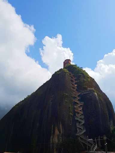 A vertical shot of El Penon de Guatape under a blue cloudy sky in Colombia
