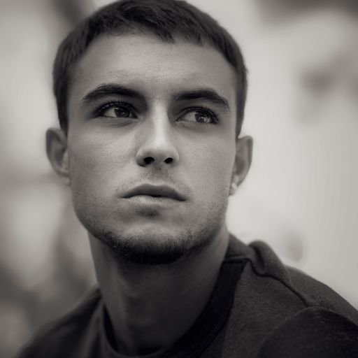 A grayscale portrait of a young bearded handsome Spanish male against the blurry background