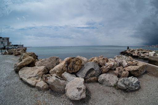 A panoramic shot of the rocky beach of the ocean and a cloudy, gloomy sky