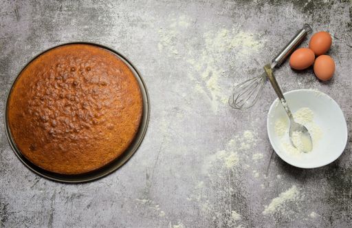 A top view shot of a homemade pie on a gray surface and flour for the preparation