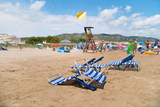 Valencian Community, Spain - August 2021. Empty white and blue plastic sun loungers on the beach. Beach vacation without people in Alcossebre.
